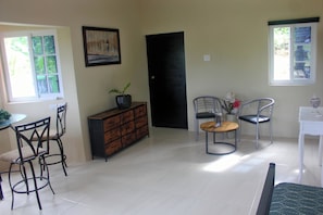 A room with a dining area, a black door, a painting, and a window with a view.
