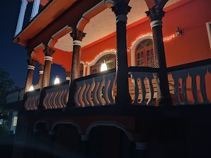 A building with ornate columns and a balcony with lights.