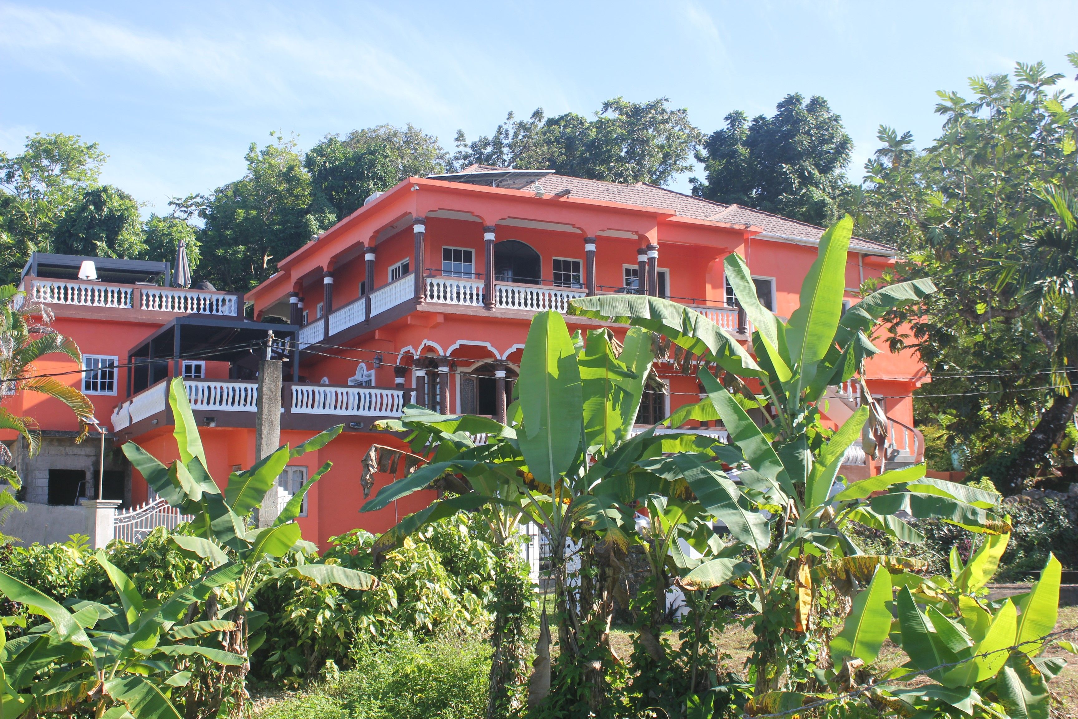 A multi-story building with balconies, surrounded by greenery.