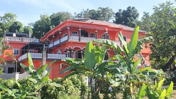 A multi-story building with balconies, surrounded by greenery.