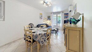 A dining area with a table set for four, a sofa, and a cabinet. - Le Bastidon Provençal T3 Terrace 3min from the Beach (Saint-Raphaël)