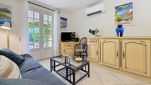 A living room with a sofa, a glass coffee table, a television, and a cabinet. - Le Bastidon Provençal T3 Terrace 3min from the Beach (Saint-Raphaël)