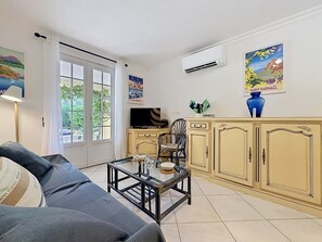 Ein Wohnzimmer mit einer Couch, einem Glastisch, einem Fernseher und einem Schrank.