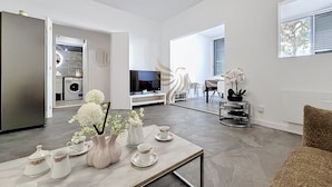 A modern living room with a dining area, a kitchen in the background, and a TV. - L'instant Nadir 5p à 2 pas Port Fréjus garage wifi (Fréjus)