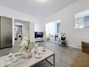 Ein modernes Wohnzimmer mit Essbereich, einer Küche im Hintergrund und einem Fernseher.
