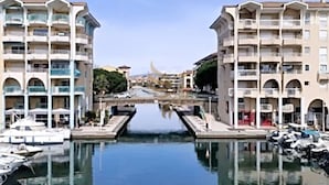 A waterfront hotel with multiple balconies, a canal in the foreground, and boats docked nearby. - L'instant Nadir 5p à 2 pas Port Fréjus garage wifi (Fréjus)