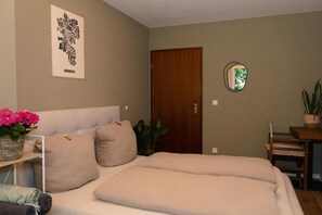 A bedroom with a bed, pillows, a mirror, a door, and a plant. - City retreat with terrace (Würzburg)