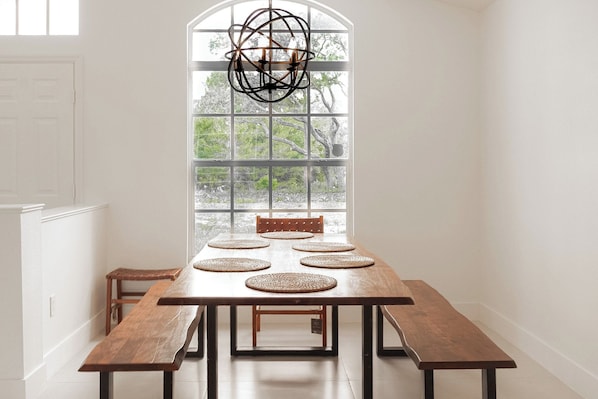 A dining room with a large window, wooden table, and benches.