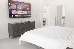 Un dormitorio con cama, cómoda y televisor en la pared mostrando diversas aplicaciones.