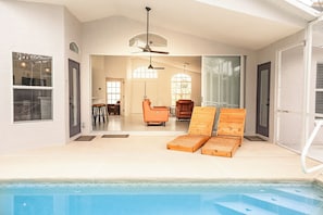 A swimming pool with lounge chairs and a ceiling fan.