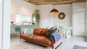 Una sala de estar moderna con sofá, mesa de comedor y zona de cocina.