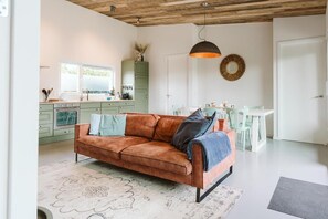 Ein modernes Wohnzimmer mit einer Couch, einem Esstisch und einer Küchenzeile.