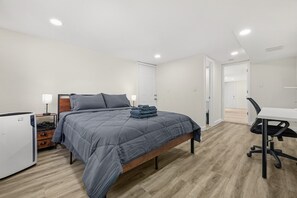 Une chambre à coucher comprenant un lit, une table de chevet, une lampe et un bureau avec une chaise.