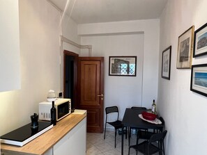 Una cocina compacta con microondas, cafetera y una pequeña mesa de comedor con sillas.
