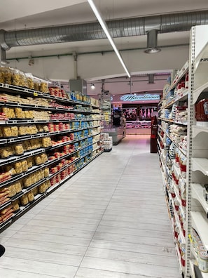 A grocery aisle with pasta and canned goods on shelves, a bakery section in the background, and a tiled floor. - Romaamor Casavacanze apartments rent vacation (Roma)