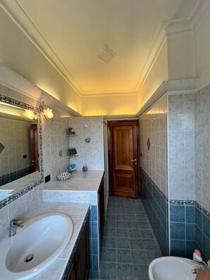 Un baño con dos lavamanos, ducha y espejo con luces decorativas.