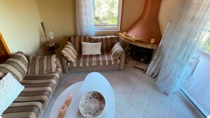 A cozy living room with a sofa, a fireplace, a window, and a tiled floor. - Large Sea View Villa Near Athens Airport (Artemis)