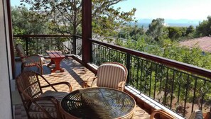 A balcony with wicker furniture, a glass table, and a view of the landscape.