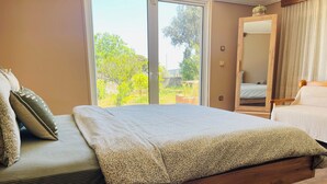 A bedroom with a bed, a wooden headboard, a large window, and a mirror. - Large Sea View Villa Near Athens Airport (Artemis)