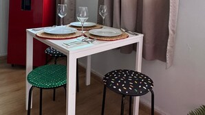 A dining area with a white table, two chairs, a red refrigerator, and a hanging plant. - Completely private property GDL (Zapopan)