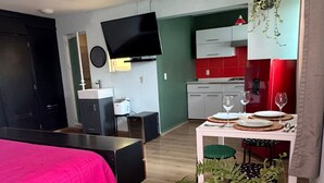 A modern hotel room with a bed, a TV, a kitchenette, and a dining area. - Completely private property GDL (Zapopan)