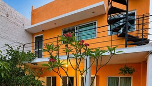 A modern two-story building with a bright orange facade, a spiral staircase, and outdoor seating area with white furniture. - Completely private property GDL (Zapopan)