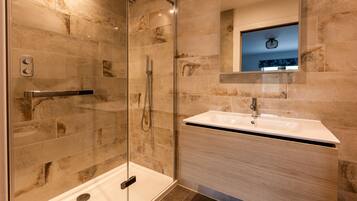 A modern bathroom with a glass-enclosed shower, a white sink, and a mirror above the sink.