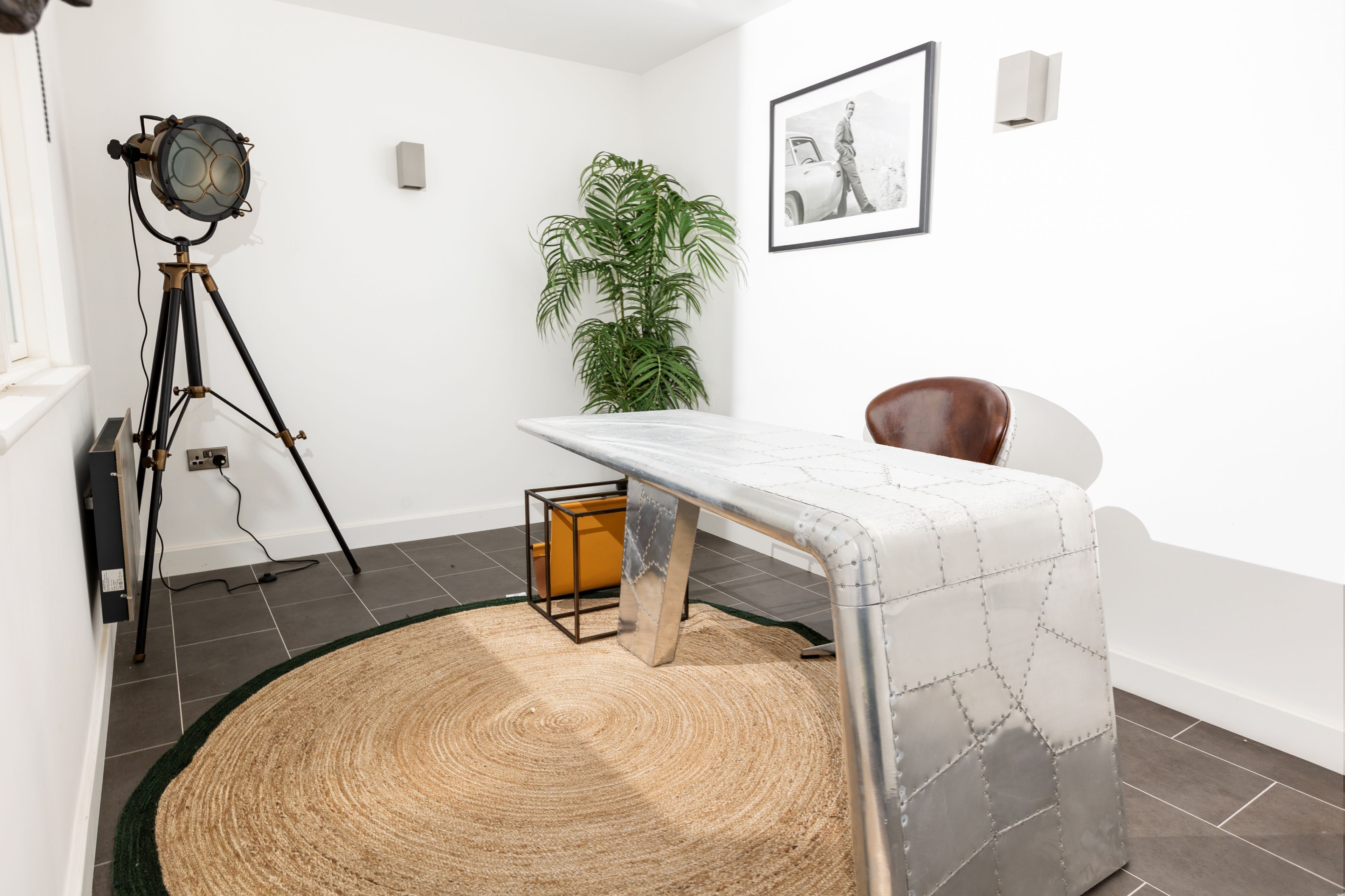 Een kamer met een op een statief gemonteerde camera, een ingelijste foto aan de muur, een kamerplant en een stoel.