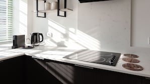 Una cocina moderna con estufa integrada, cafetera y estantería.