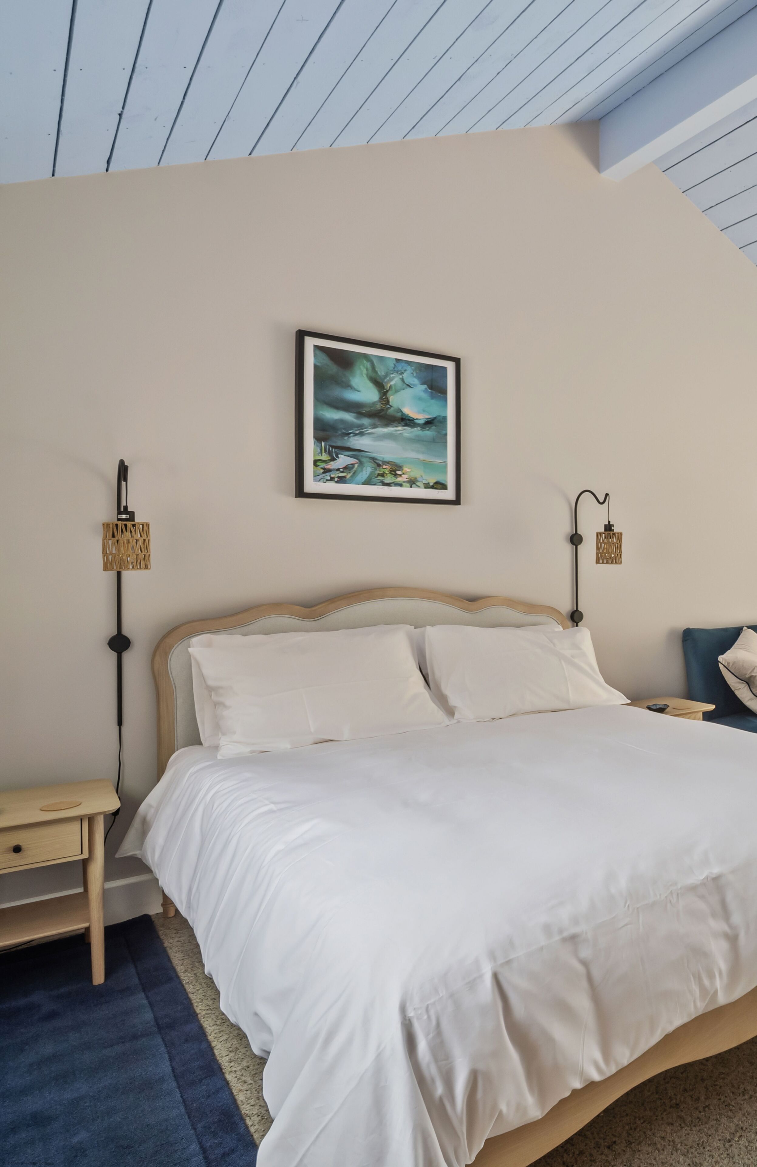 Ein Schlafzimmer mit einem Bett, einem Nachttisch, einer Lampe und einem Bild an der Wand.