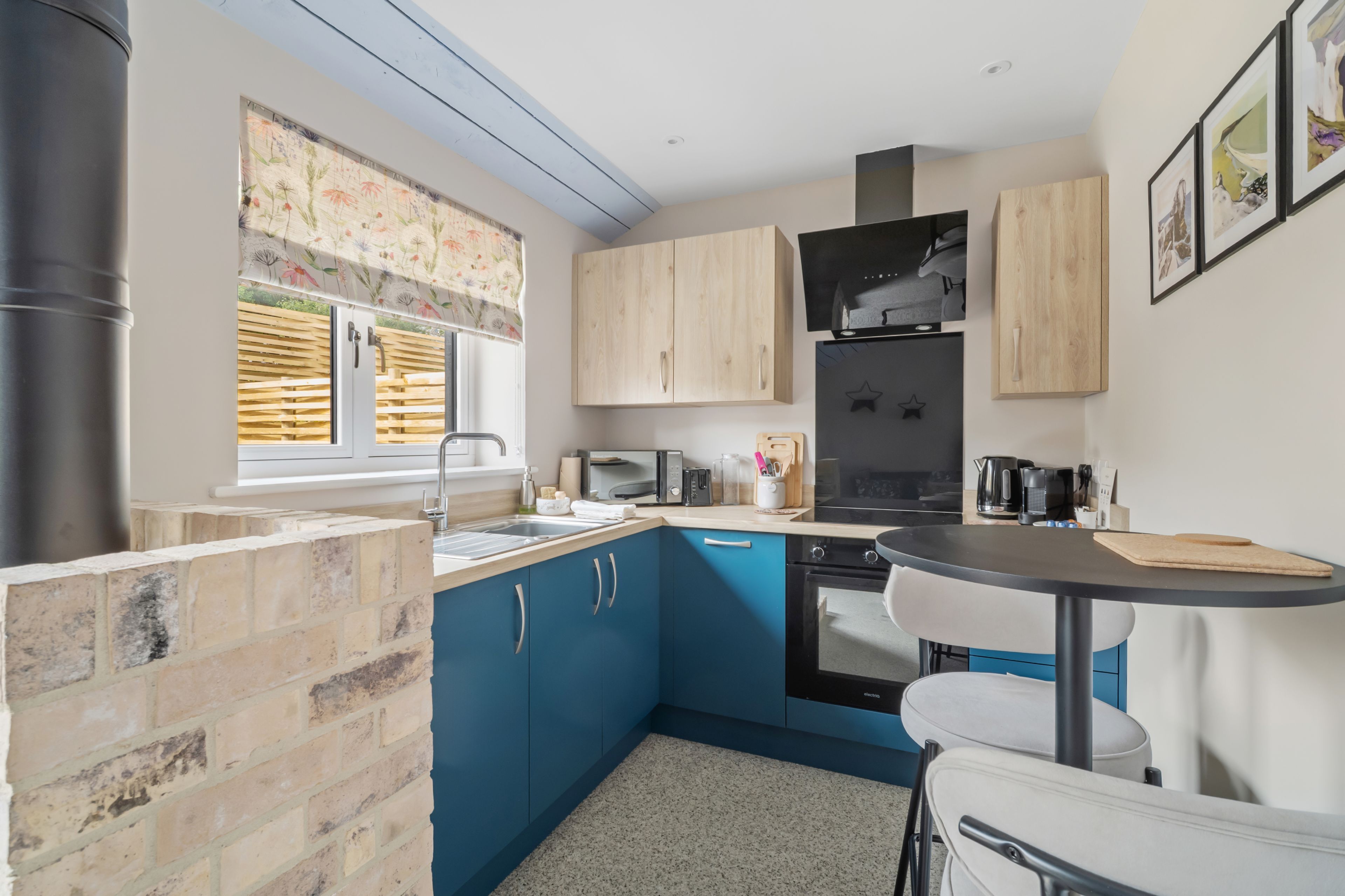 Una cocina compacta con armarios azules, una estufa negra y una pequeña mesa de comedor.