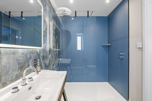 Une salle de bain moderne avec un grand miroir, une baignoire, une douche et des toilettes.