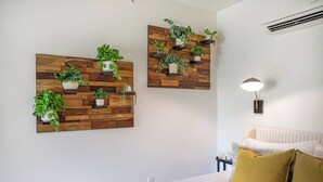 Un dormitorio con cama, mesita de noche, lámpara y dos macetas colgantes en la pared.