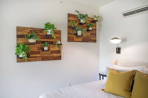 A bedroom with a bed, a bedside table, a lamp, and two wall-mounted plant displays.