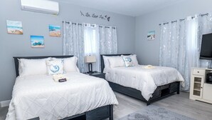 A bedroom with two beds, a TV, and a small cabinet. - Paradise in Bloom - Spacious  5-bedroom Caribbean estate in Cable Beach, Nassau. (Nassau)