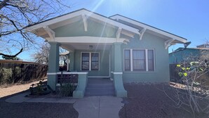 A house with a porch, a front door, and a small garden area. - Historic updated 2-bedroom bungalow in a walkable neighborhood (Tucson)