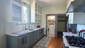 A modern kitchen with a central island, built-in appliances, and a view into the dining area. - Historic updated 2-bedroom bungalow in a walkable neighborhood (Tucson)