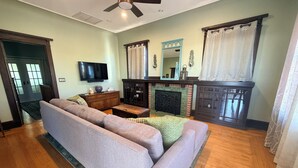 A living room with a sofa, a fireplace, a television, and a ceiling fan. - Historic updated 2-bedroom bungalow in a walkable neighborhood (Tucson)