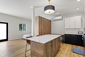 A modern kitchen with a marble island, wooden accent wall, and black cabinets. - Peaceful 1 bed suite in fantastic location.  Close to everything. (Redmond)