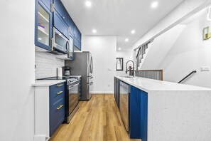 Eine moderne Küche mit blauen Schränken, Edelstahlgeräten und einer weißen Arbeitsplatte.