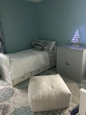 Una camera da letto con un letto, un comodino, un armadio e una piccola decorazione a forma di barca a vela.