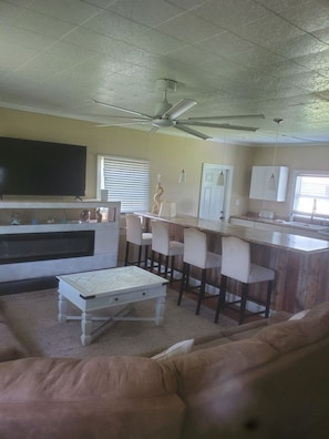 A living room with a sofa, a coffee table, a TV, and a ceiling fan. - 2-bedroom house in perfect Morehead City with AC (Morehead City)
