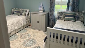 Une chambre avec deux lits, une armoire, un tapis à motifs et une fenêtre avec des rideaux.