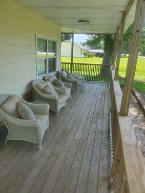 A covered porch with wicker furniture and a view of a green lawn. - 2-bedroom house in perfect Morehead City with AC (Morehead City)