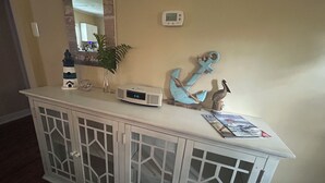 Un meuble blanc avec des portes en verre, une horloge numérique, des objets décoratifs et un thermostat fixé au mur.