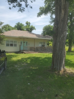 A single-story house with a front porch, a garage, and a large tree in front. - 2-bedroom house in perfect Morehead City with AC (Morehead City)