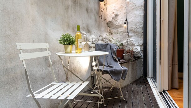 A small outdoor seating area with a table and chairs, a bottle of wine, and a potted plant. - Patio de Santa Catarina (N77) (Porto)