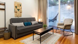A modern living room with a sofa, armchair, coffee table, and a large window with a view. - Patio de Santa Catarina (N77) (Porto)