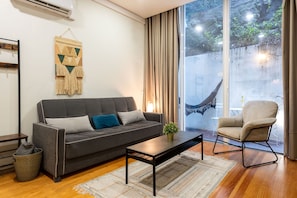 Ein modernes Wohnzimmer mit einer Couch, einem Sessel, einem Couchtisch und einem großen Fenster mit Aussicht.