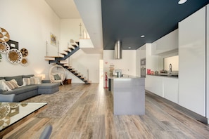Un intérieur moderne comprenant un espace de vie, un escalier, une cuisine et un coin repas.